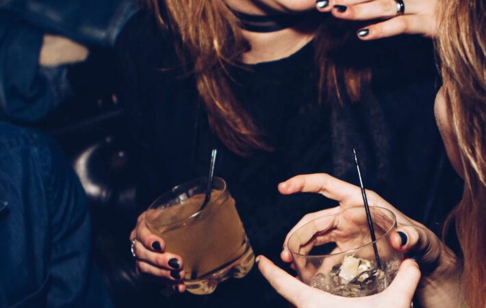 Zwei Freundinnen auf einer Party mit Drinks in ihren Händen